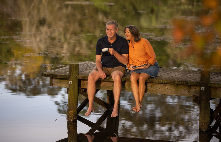 Couple sitting on dock over the lake having a cup of coffee at GemLife Moreton Bay